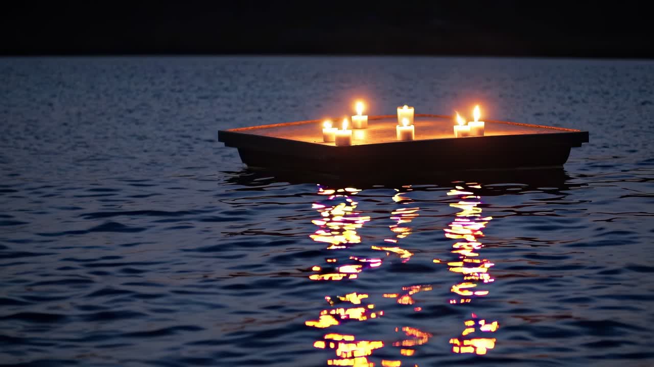 Floating candle platform illuminates tranquil water surface, creating a serene ambiance with reflections in a peaceful nighttime setting