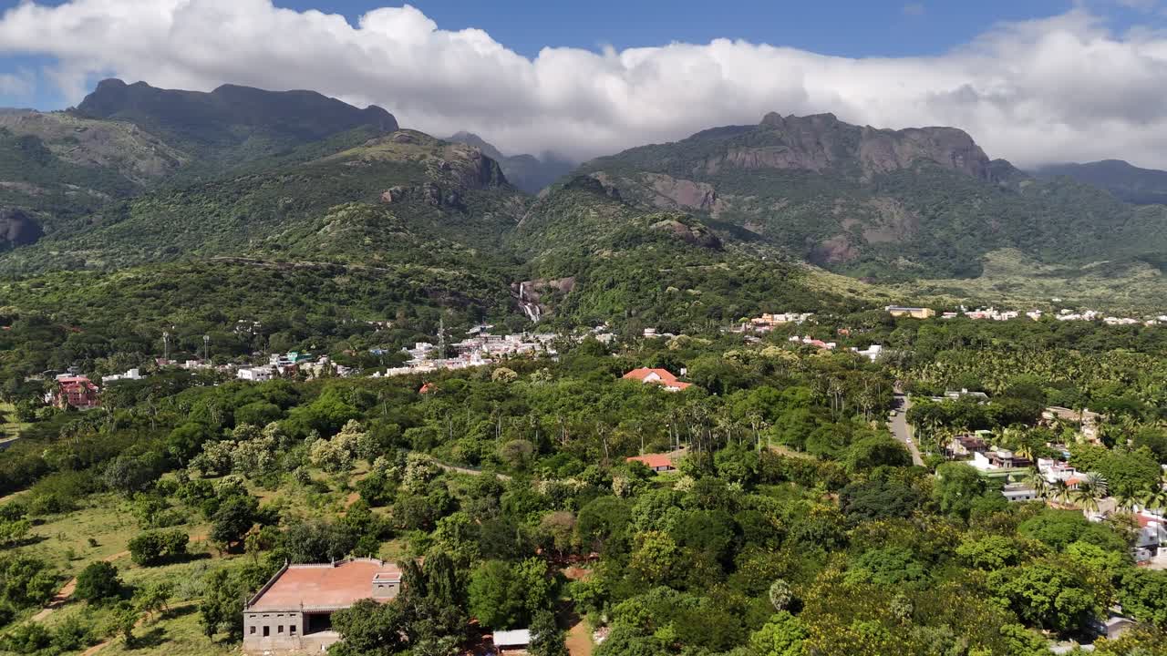 Aerial view of Courtallam nestled in the Western Ghats, showcasing lush forests, cascading waterfalls, and colorful townscapes surrounded by tropical greenery