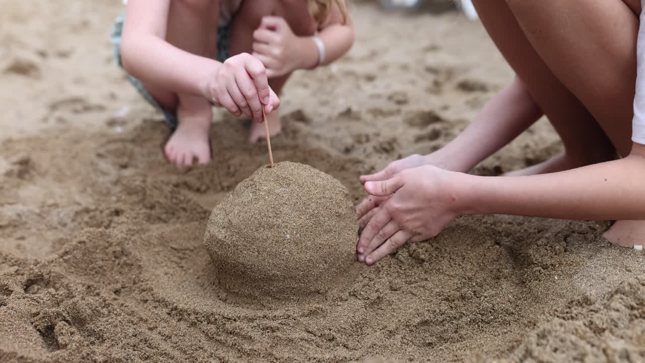 Mor och dotter bygger en konstruktion av sand på stranden