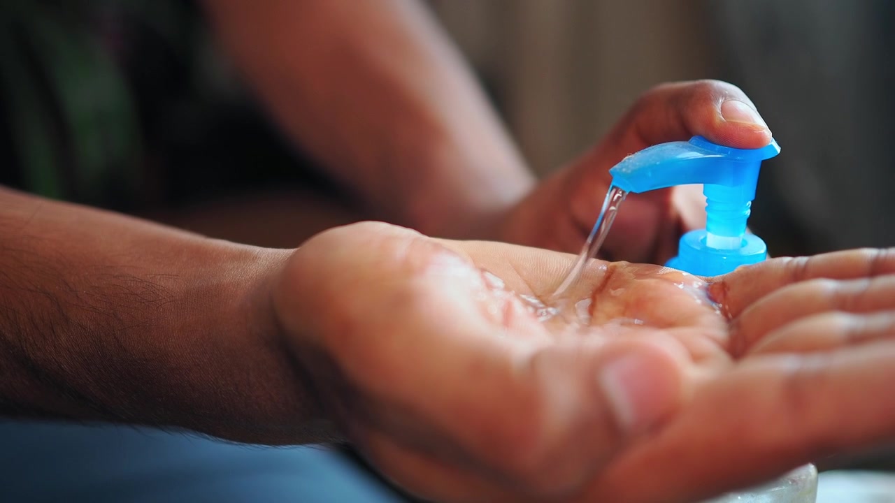 Persona che usa gel disinfettante per mani da un flacone con dosatore.