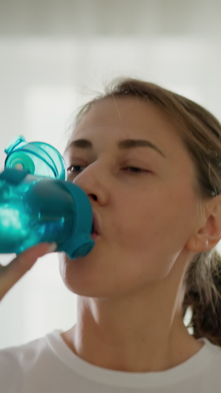 mujer atleta corre en una cinta de correr bebiendo agua de cerca. deportista trabaja en un club de fitness con ropa deportiva en cámara lenta. regímenes de fitness internos