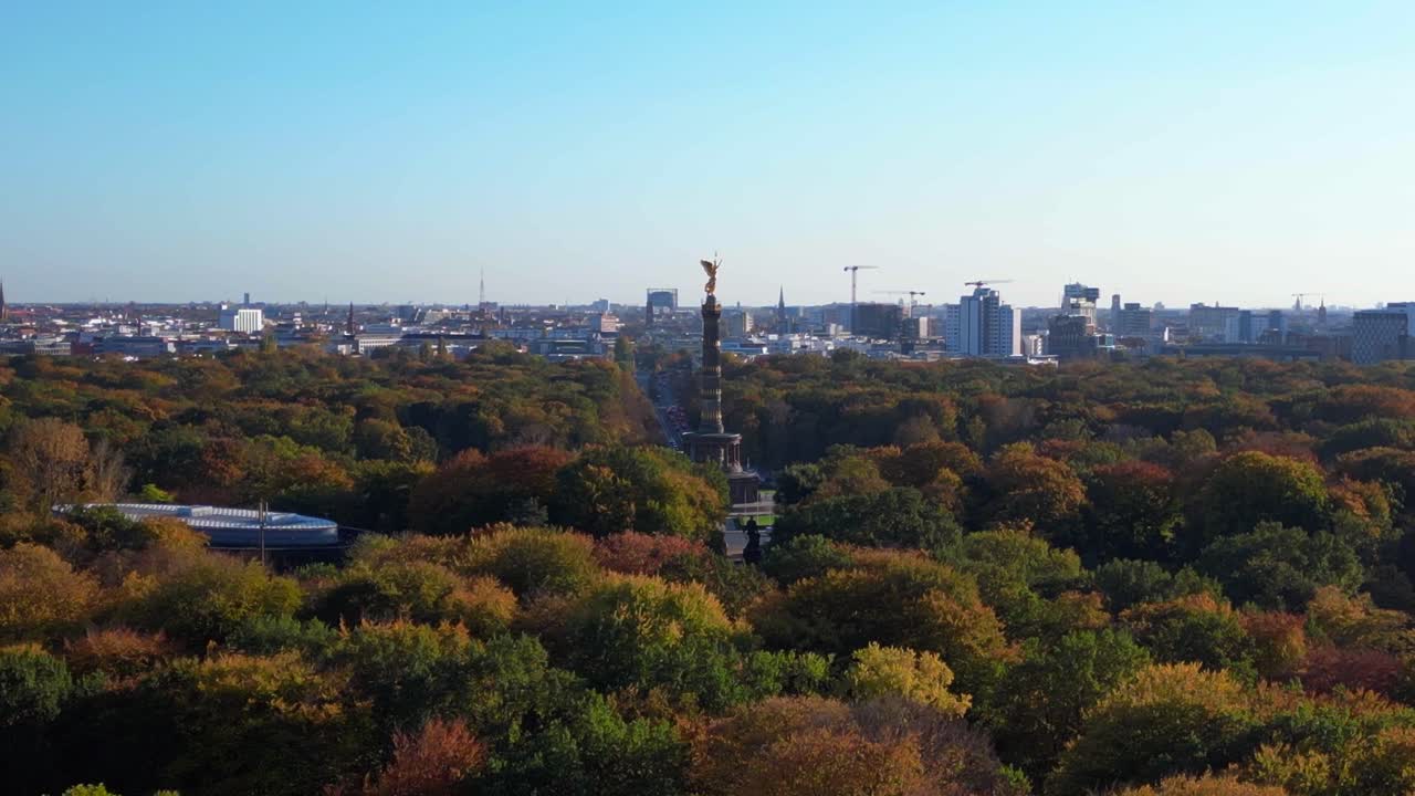 iconic berlin victory column rising above the vibrant autumn foliage of tiergarten park, with the cityscape in the background. Smooth aerial view flight wide orbit overview drone