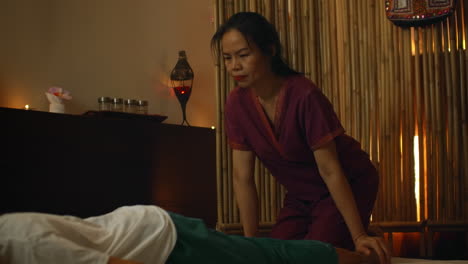 asian woman performs traditional thai massage to beautiful european woman. rehabilitation and treatment after injuries with the help of massage. relax and rest from massage of legs arms and back. therapeutic massage