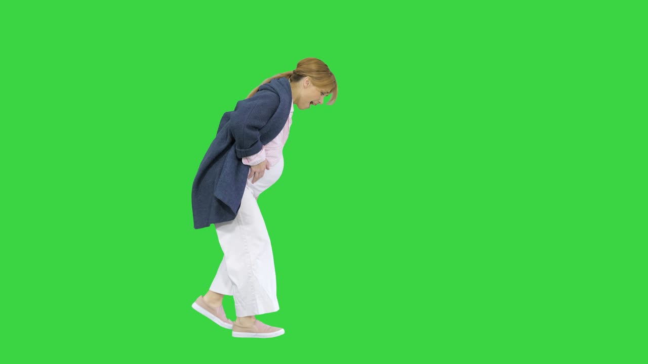 Walking pregnant woman has labour pain due to the contraction on a Green Screen, Chroma Key