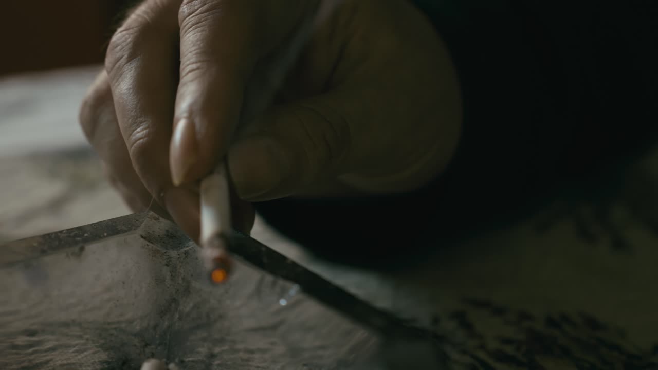 Hand holding burning cigarette over dirty glass ashtray CLOSE-UP SLIDE