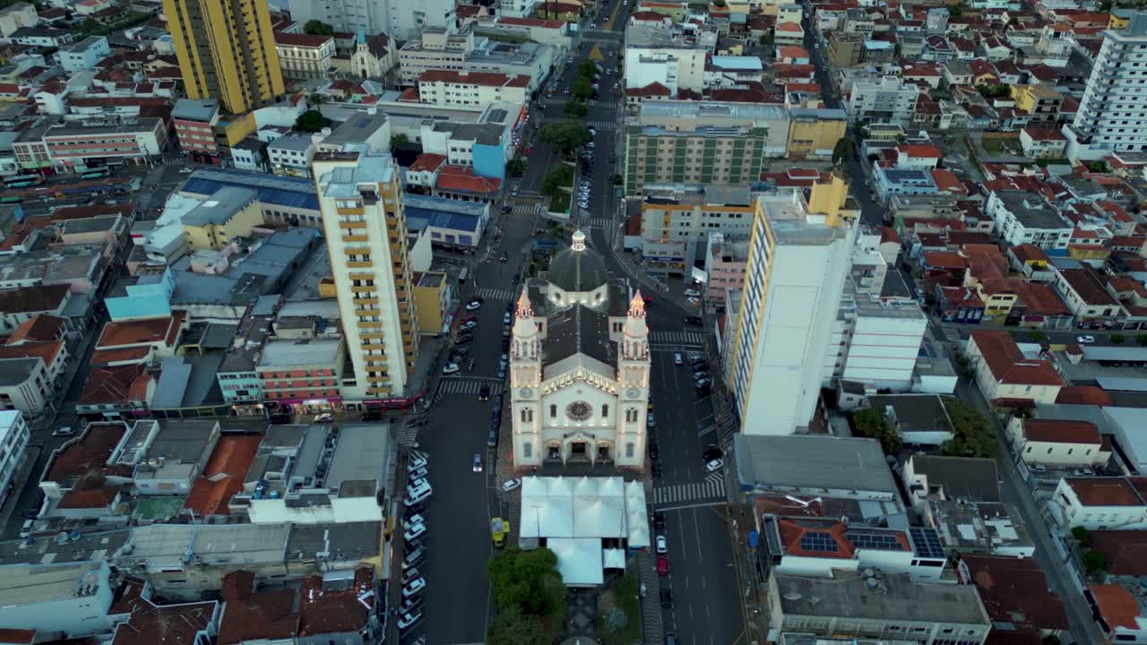 City center of Pouso Alegre, Minas Gerais, focusing on a historic cathedral surrounded by tall, modern high-rise buildings and dense commercial development