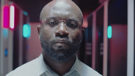 portrait of a man with glasses in a neon-lit room
