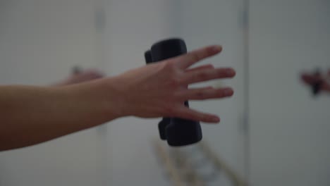 un primer plano de las manos de una dama en un gimnasio ejerciendo sus manos con pequeñas pesas en un gimnasio