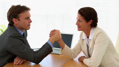 Business-people-arm-wrestling-at-desk