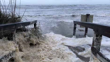 la marejada ciclónica y la espuma del mar cubren la pasarela de la playa del huracán nicole en florida