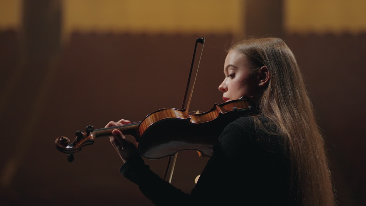 una mujer joven está practicando el violín en una escuela de música retrato de una violinista en un salón de música