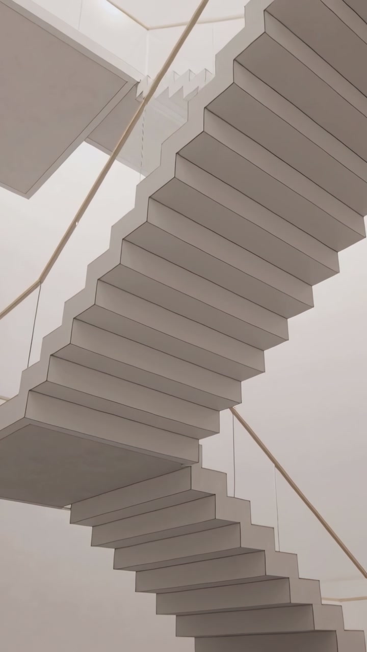 Vertical video: Tilting camera revealing cantilevered zigzag staircase in atrium, showing shape