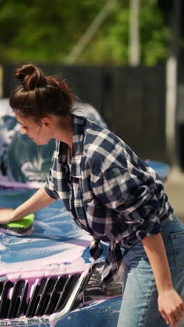 woman washing a car with soap and sponge