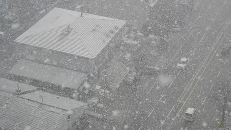 heavy snowfall in city with cars and buildings from above