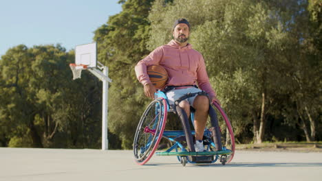 hombre barbudo de mediana edad en silla de ruedas deportiva en la cancha de baloncesto
