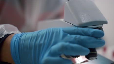 vista de cerca de la mano del científico usando el microscopio en el laboratorio