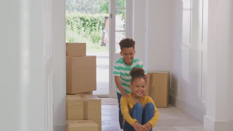 Chica-Empujando-A-Su-Hermano-En-Patineta-Entre-Cajas-En-Movimiento-En-El-Día