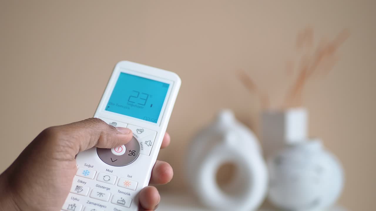 에어컨 원격 제어기를 들고 있는 사람