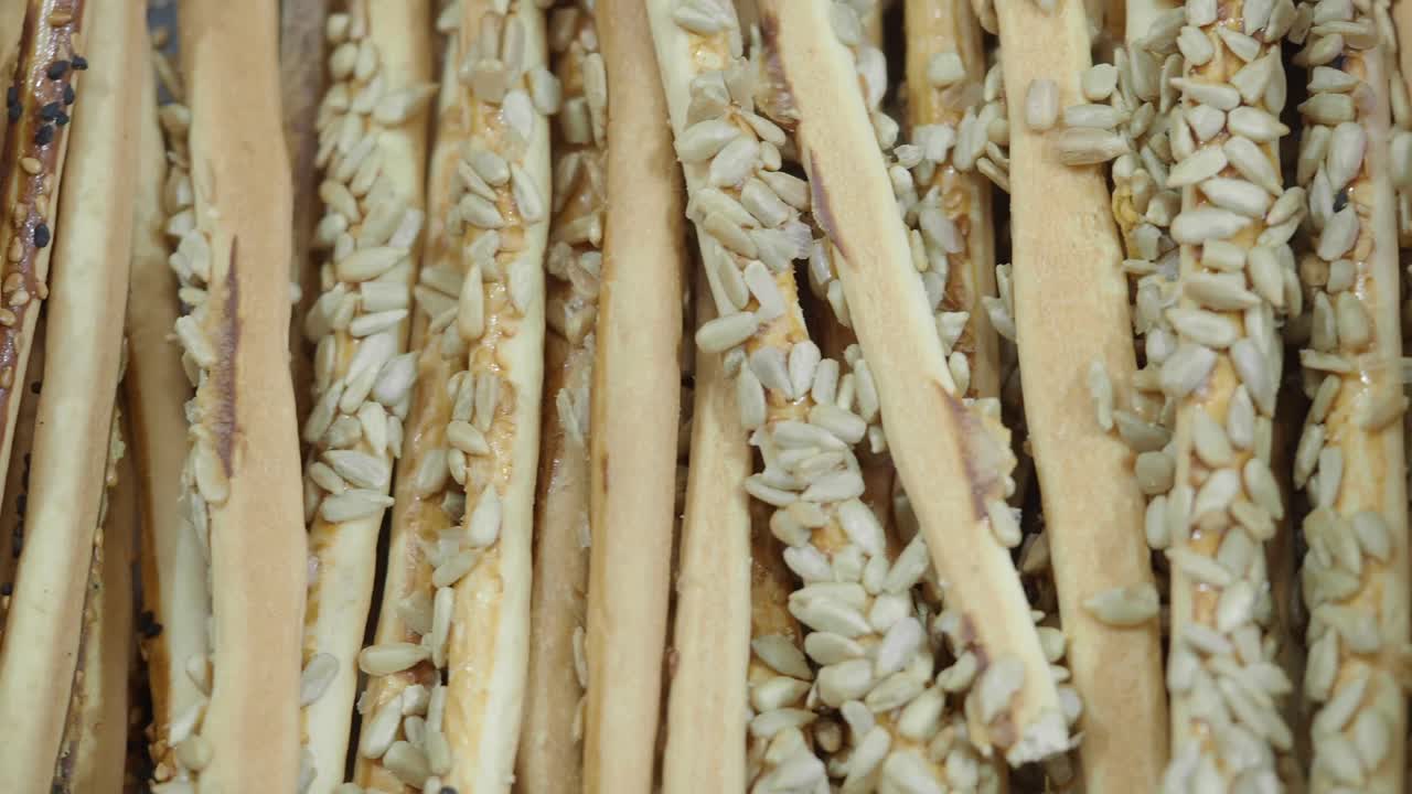 Close-Up Pan of Grissini Breadsticks with Sunflower and Sesame Seeds