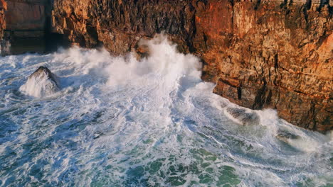 foaming sea waves hitting rocky shore with splashes aerial view. dangerous ocean