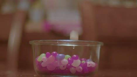 multi colored jelly beans falling into a clear glass bowl in 64 fps