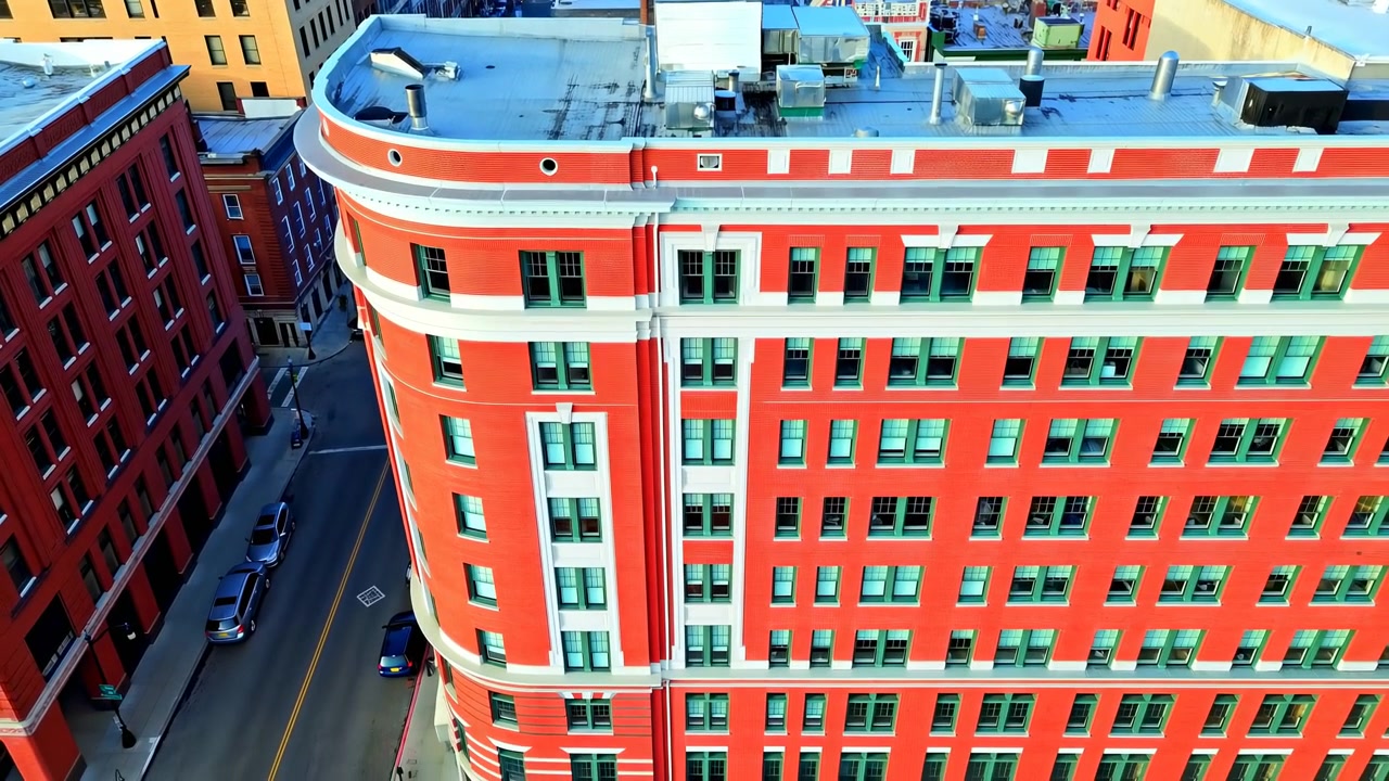 Vista Aérea de Edifício de Esquina de Tijolo Vermelho, Fachada Urbana Vibrante com Janelas de Moldura Verde, Cornija Curva