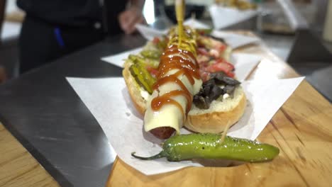 slow motion shot of a hot dog being covered with sauces and mustard