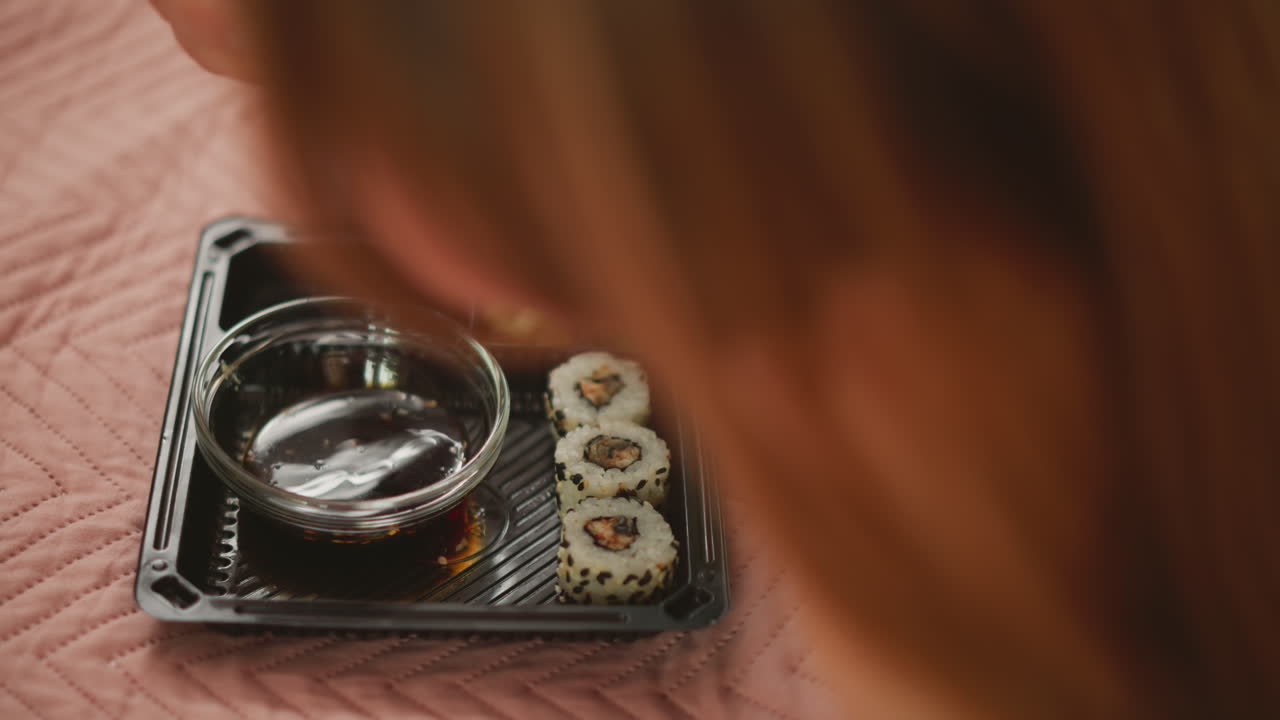 mujer comiendo sushi con palillos