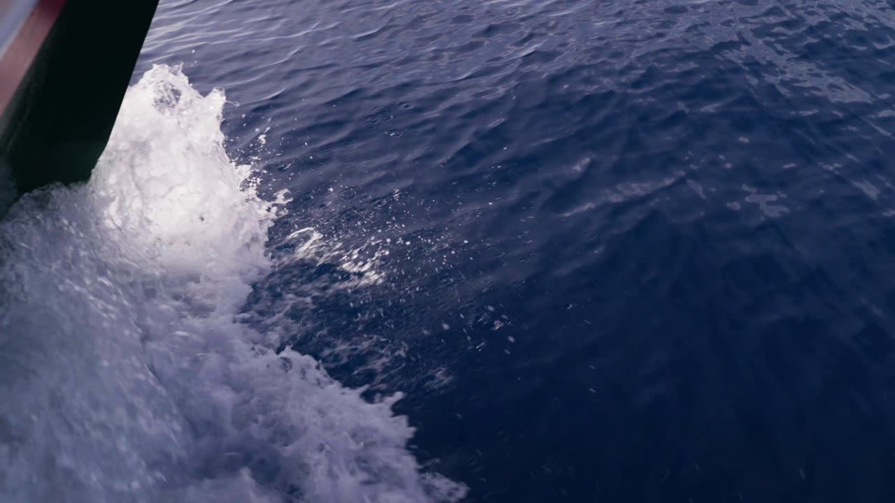 From the boat, the waves crash against the bow, sending splashes of water into the air. The sunlight reflects off the shimmering surface, creating a sparkling dance of light on the ocean.