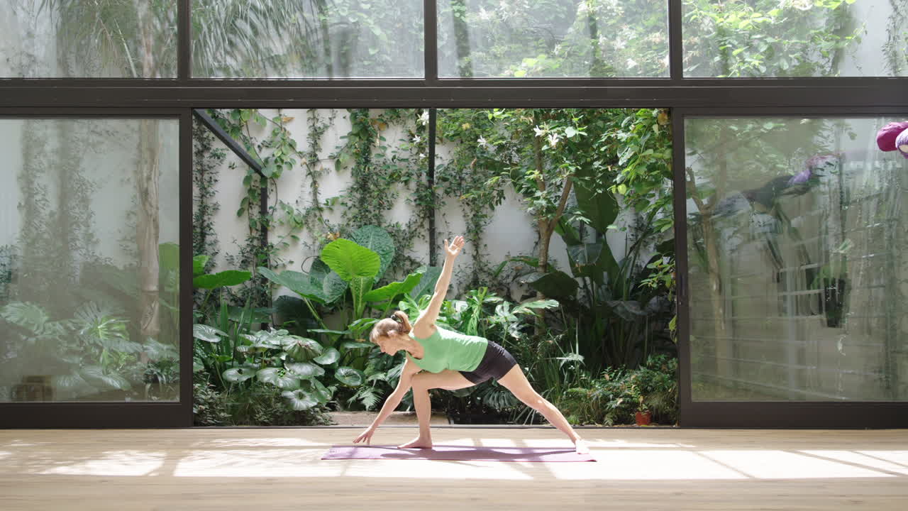 Frau praktiziert Halbmond-Yoga-Pose in einem ruhigen Indoor-Gartenstudio