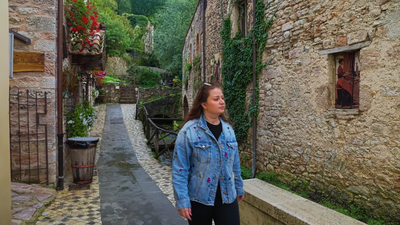 una mujer en el encantador pueblo medieval de arroyos de rasiglia en perugia, umbría, italia