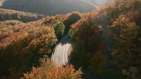 Bellas-Imágenes-Aéreas-De-Automóviles-Conduciendo-Por-Una-Carretera-Escénica-Que-Serpentea-En-Un-Bosque-De-Colores-Otoñales