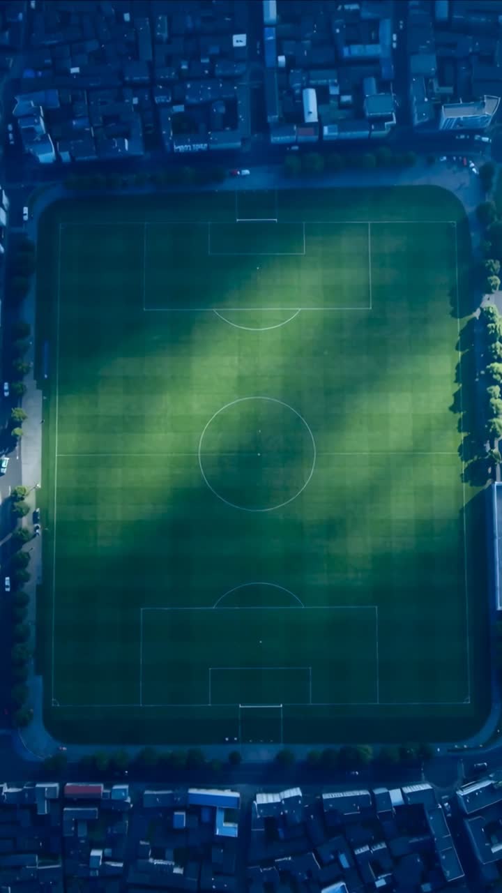 Video verticale: Nuvole che passano proiettano la luce del sole su un campo da calcio in un'area urbana, rivelando le porte.