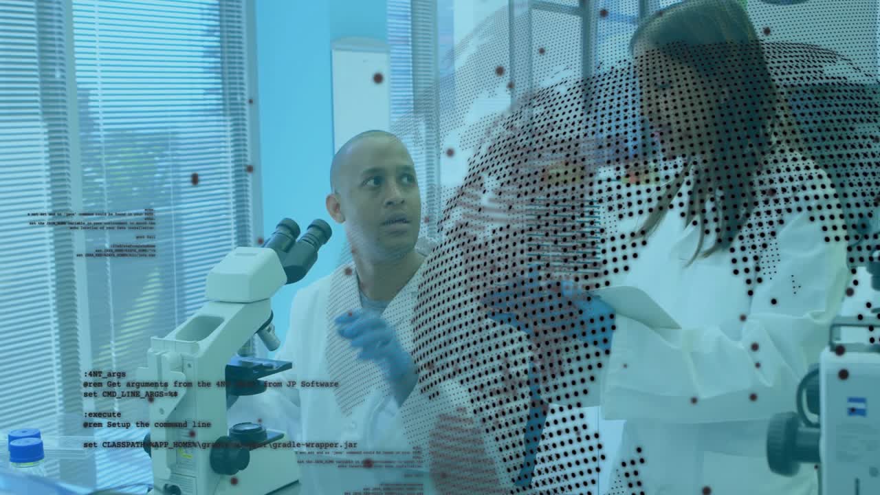 Lab scientist adjusting microscope focus as colleague tapping tablet, activating data globe overlay