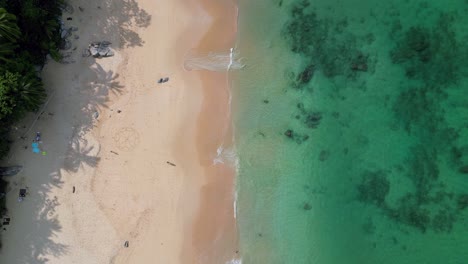 top-down view of naithon beach in tropical phuket, thailand, with golden sand, palm shadows, and clear turquoise water.