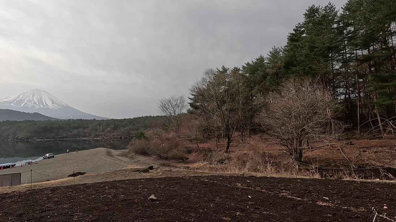 Panoramic view of Mount Fuji with surrounding trees and lake, captured on a cloudy day in Kawaguchiko, Japan