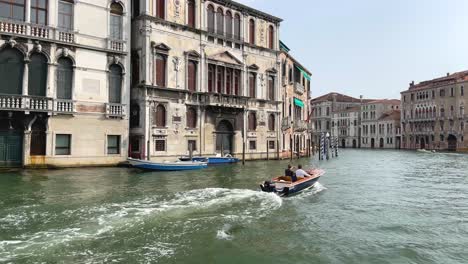 two wealthy men in motor boat sightseeing venice, italy on grand canal