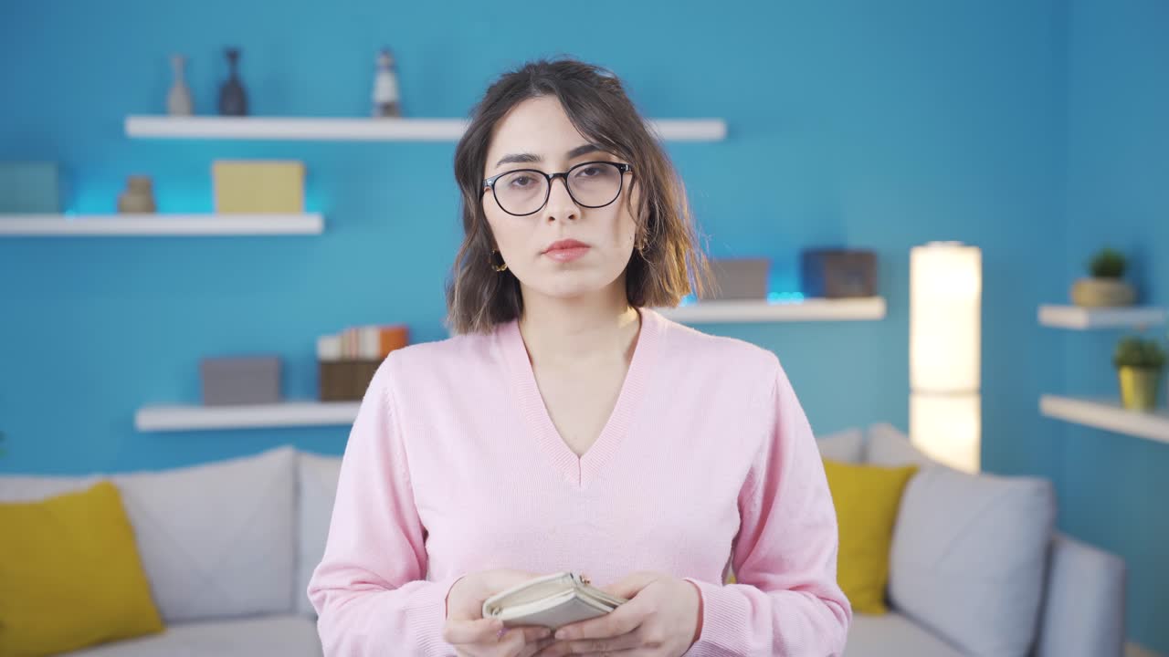 una joven quebrada mirando su billetera.