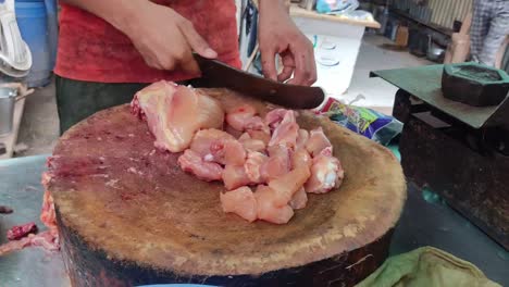un carnicero profesional cortando pollo en pedazos en la india