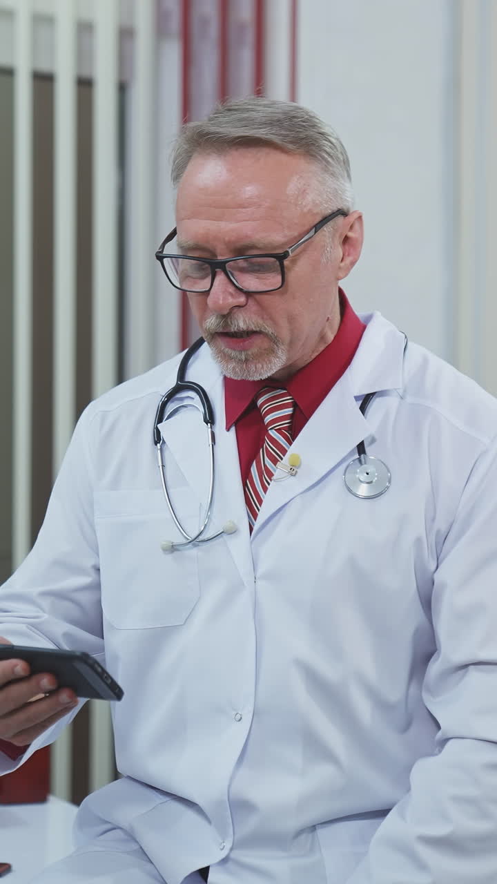 Doctor speaks with patient. Doctor with stethoscope in surgery office talking to patient online. Vertical video