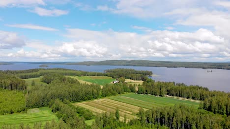 Vista-Aérea-De-Tierras-De-Cultivo-Con-Un-Lago-E-Islas-Al-Fondo-En-Un-Día-Soleado-De-Verano