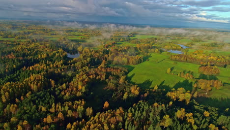 Panorama-Einer-Herbstlandschaft-Mit-Bunten-Bäumen,-Wiesen-Und-Seen-Bei-Einem-Nebligen-Herbstsonnenuntergang