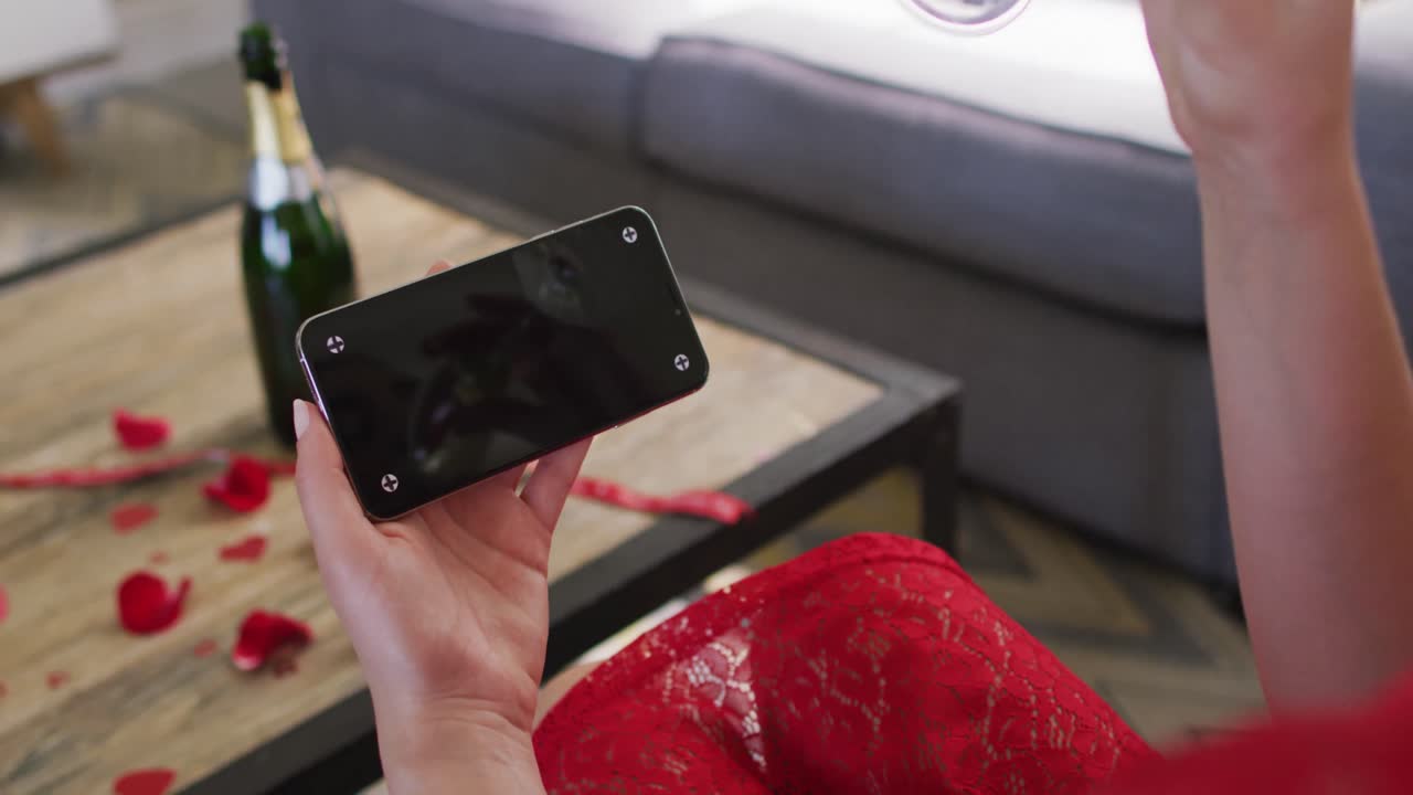 Caucasian woman with champagne making valentine's day video call on smartphone, copy space on screen