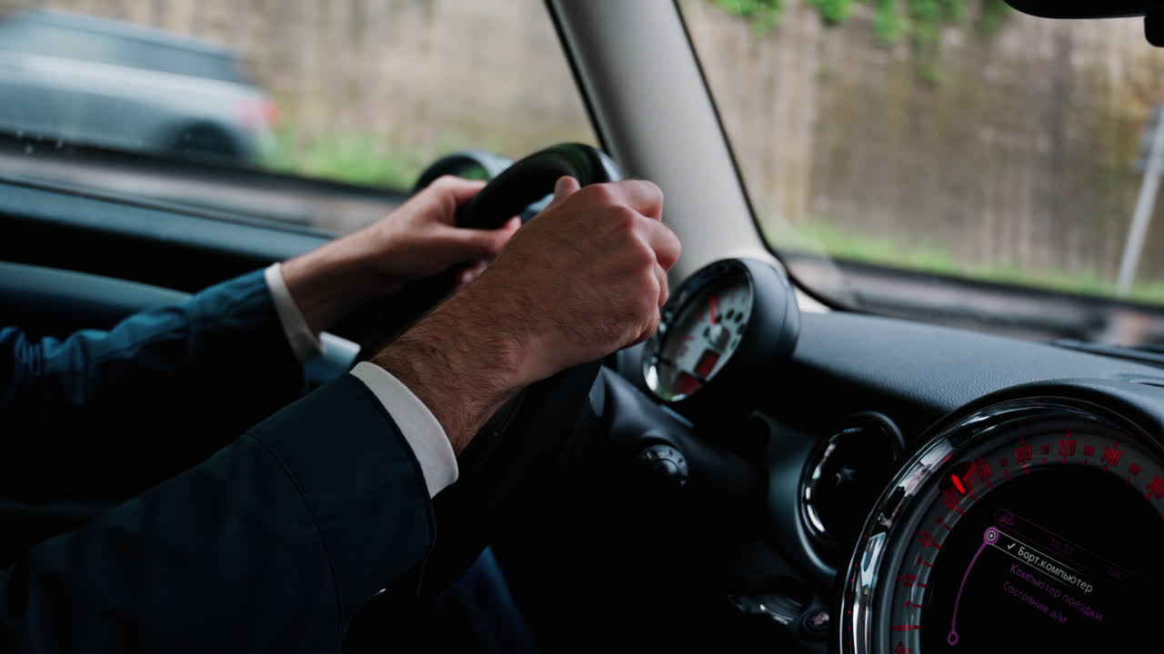 Close up of a man's hands on a steering wheel, driving a car on the road