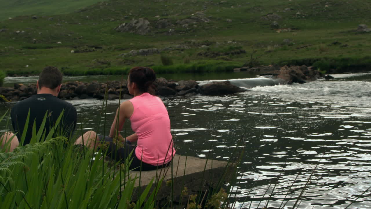 pareja relajándose junto a un lago tranquilo en el campo