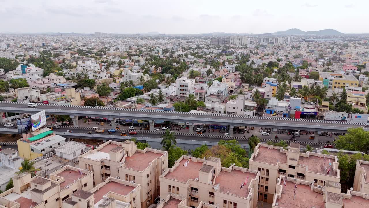 Drone4 view of densely populated urban area featuring buildings and trees with a roadway or flyover cutting across the city. Congested city