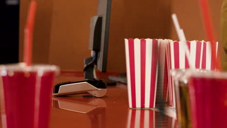 camera focuses on the hands of the employee giving a movie ticket to a person and then using the credit card in the point of sale terminal