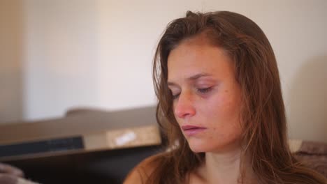 a close up portrait shot of a young woman with wounds and bruises, stares with a blank look and starts crying