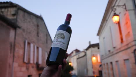 hand holding wine bottle in bordeaux street