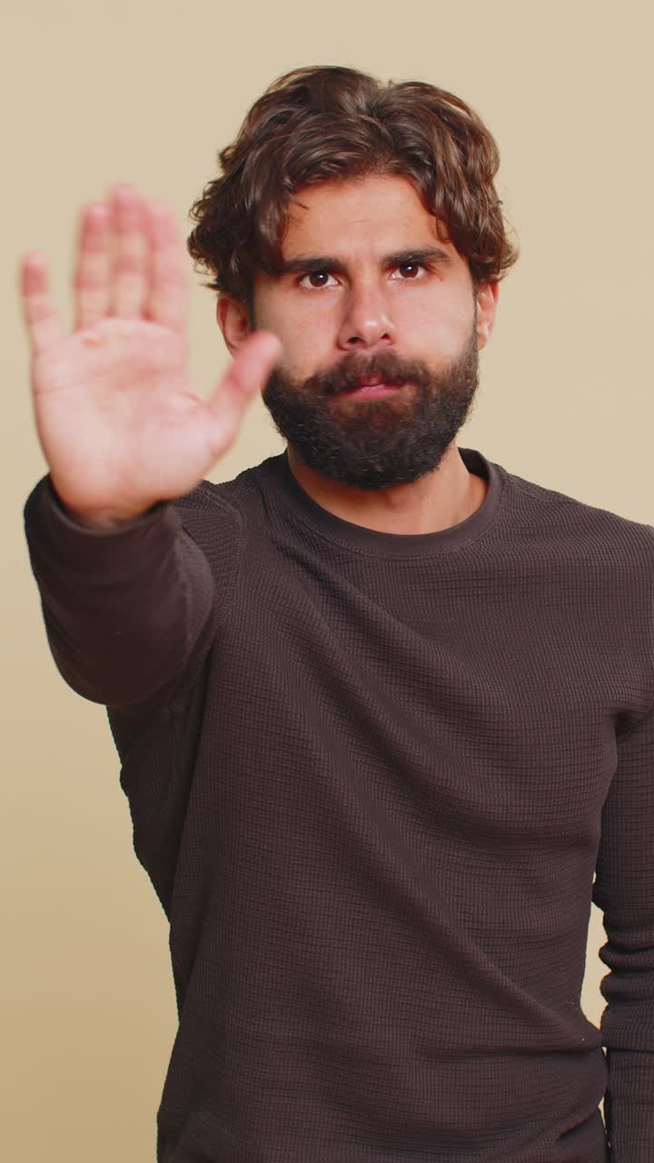 Hindu man says no hold palm in stop gesture warning of finish prohibited access on beige background
